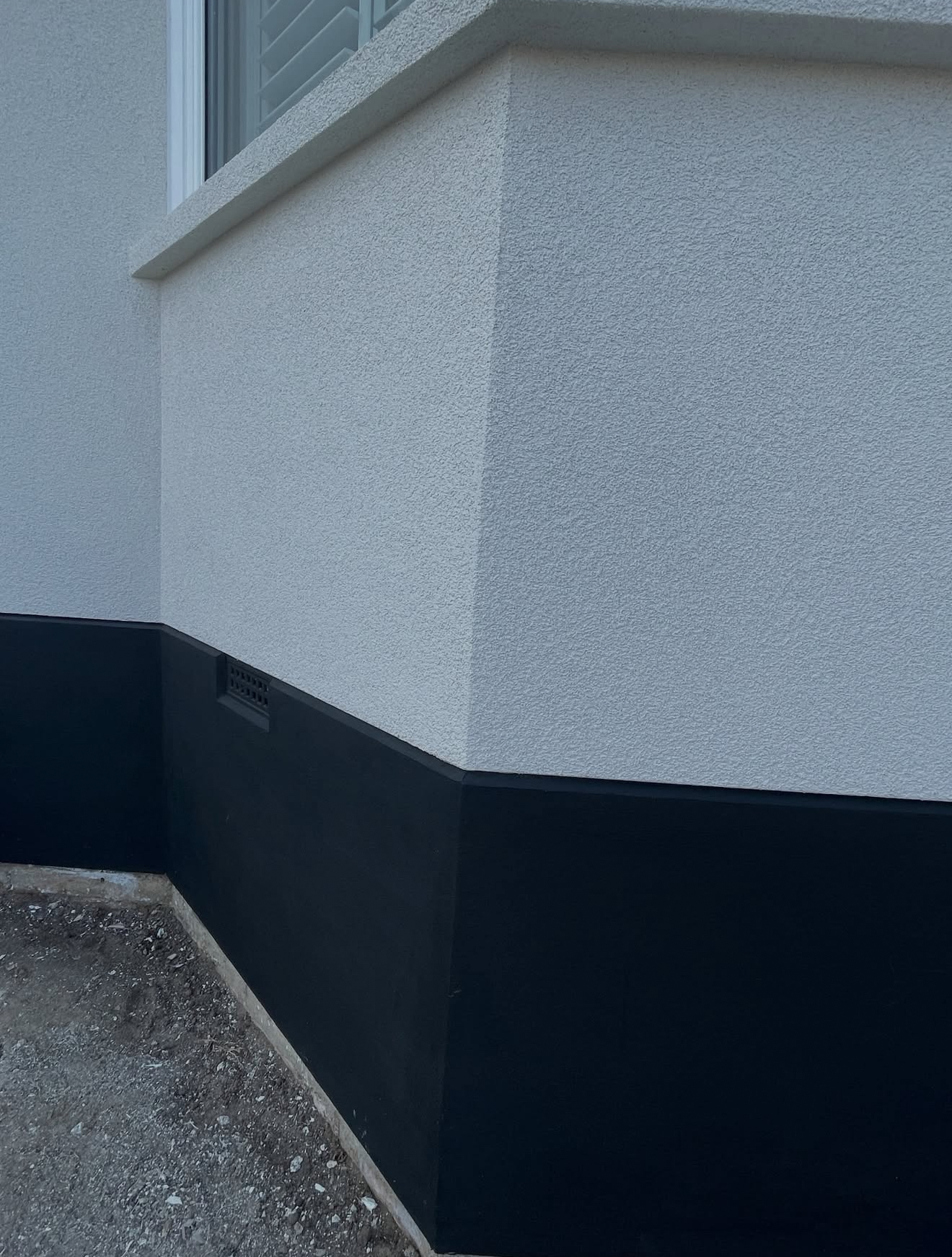 Rendered wall corner with a dark plinth